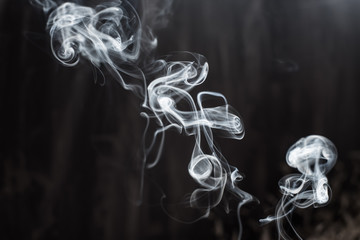 Image of backlit puffs of smoke, on a dark background.