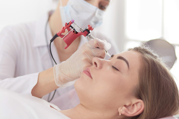 A young girl having red lips permanent makeup, micropigmentation