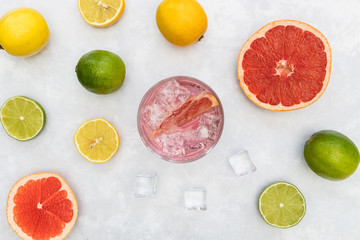 Pink gin tonic vodka soda fruit grapefruit cocktail drink in glass with ice, top view on white...