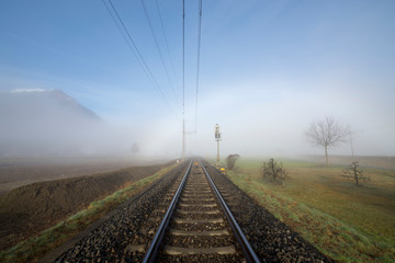 Railroad Tracks in the Fog and Mountain in Ticino, Switzerland.