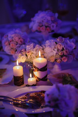 Beautiful, decorated table with flower decorations and red candles. Christmas evening or wedding party decoration.