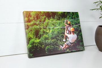 Canvas print on white table. Photo with gallery wrap method of canvas stretching on stretcher bar. Color photography with image of people on zip line. Interior decor