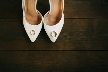 Beige high heels shoes with wedding rings.