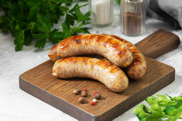 Grilled sausages on a wooden Board on a light gray kitchen table