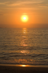 Obraz premium Photo of the setting sun over the sea. On the horizon are visible silhouettes of ships and parachutes. Sky and orange clouds