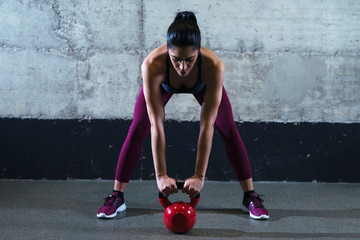 Fitness woman in sports clothes exercising with kettle bell weight in the gym. Training and sport.