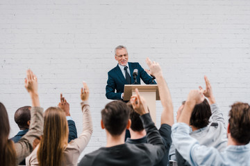 back view of journalists with raised hands near happy bearded speaker