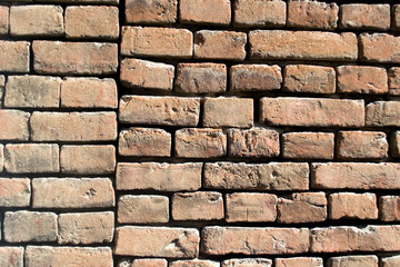 Part of the brick wall in the old town. Different bricks, whole and slightly broken. Joints of brickwork of various buildings.