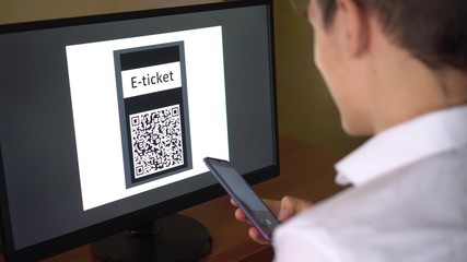 Fototapeta na wymiar A man purchases a E-Ticket with QR code online for the event, travel, trip. Electronic ticket booking, buying, payment 