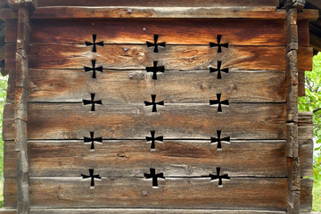 The wooden wall of a small old summer house with ventilation holes in the form of crosses. The texture of the old tree. Vintage tree structure. Tbilisi, Georgia