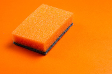 Orange sponge for cleaning on an orange background