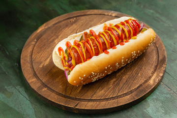 Hot dog with sausage, ketchup and mustard on wooden background