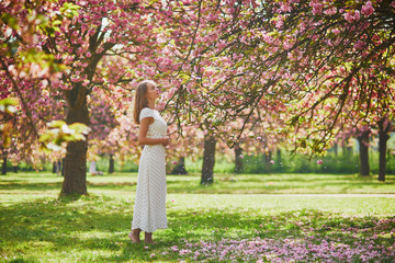 Young woman enjoying her walk in park during cherry blossom season on a nice spring day