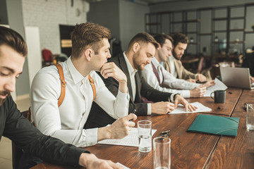 successful and confident caucasian men, business partners hold meeting in modern office. young men in formal wear discuss and planning strategies together, useful cooperation of leaders in boardroom