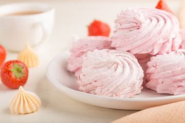 Pink strawberry homemade zephyr or marshmallow with cup of coffee on white wooden background. side view, selective focus.