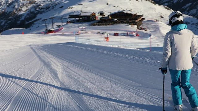 Young adult sportswoman in a ski suit and helmet skiing on an empty ski slope in the Dolomites, Livigno Italy