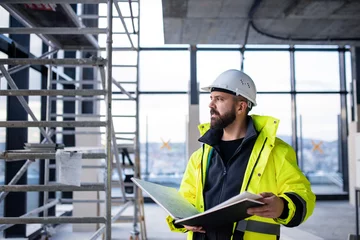 Foto op Plexiglas Man engineer standing on construction site, holding blueprints. © Halfpoint
