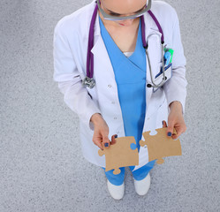 Woman doctor holding two connecting puzzle pieces