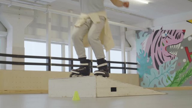 Lockdown of Caucasian male skater jumping backwards from springboard in indoor skate park
