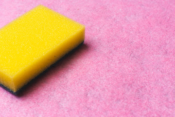 Yellow dishwasher sponge on a pink background