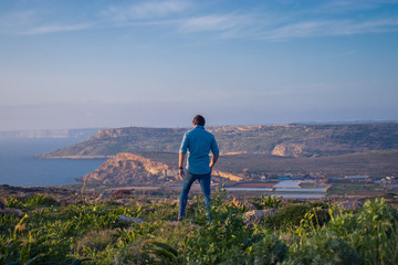 man standing in beautiful scenery watching an amazing view at the island Malta