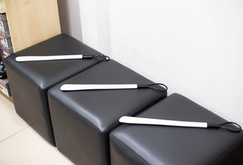 A shoehorn is lying on a black ottoman in a store. The concept of selling and buying shoes for all seasons, copy space