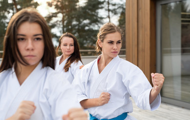 Group of young women practising karate outdoors on terrace. © Halfpoint