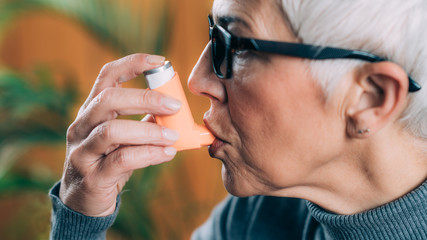 Senior Woman Using Asthma Inhaler with Extension Tube