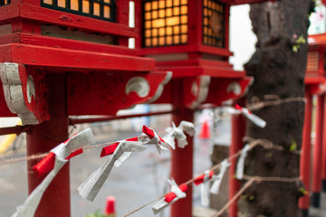 神社の赤い灯籠と紐に結ばれたおみくじ