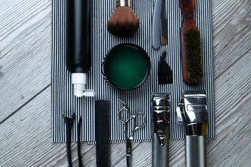 Flat lay from hairdressing accessories including: haircuts, scissors, combs, gels for styling and...