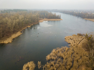 Aerial drone view. A small island on the river in Kiev in late autumn. Dry grass envelops the coast, rare trees on the island.