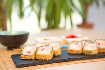 Rolls with shrimp in a black plate on a wooden table. Sushi closeup Healthy and tasty food.