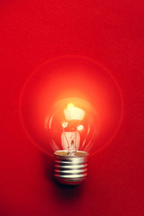 Light bulb on red background flat lay