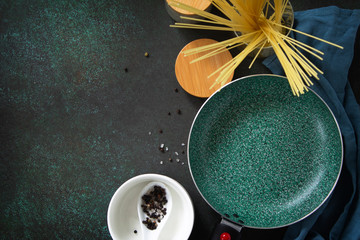 New Empty fry pan with ceramic coatingon on a stone kitchen table surrounded by Italian cuisine ingredients. Top view flat lay background. Copy space.