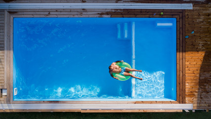 Aerial view of man lying in water in swimming pool outdoors.