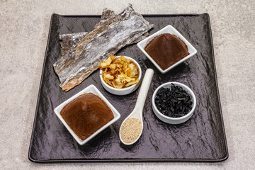 Set of traditional Japanese ingredient for cooking basic dashi broth. Algae kombu and wakame, miso paste, katsuobushi and dry granules. Black ceramic plate background