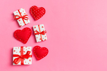 Holiday composition of gift boxes and red textile hearts on colorful background with empty space for your design. Top view of Valentine's Day concept