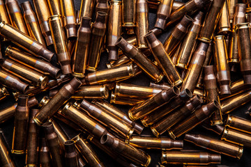 Background from empty cartridges for rifles and carbines. Shiny brass shells scattered on the...