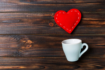 Top view of a cup and red hearts falling out from it on wooden background. Happy Valentine's Day concept