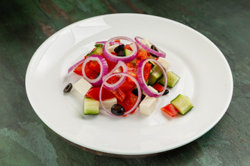 Greek salad in a white plate on a wooden background
