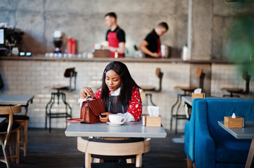 Сonfident young african american woman in smart casual wear with handbag at cafe.