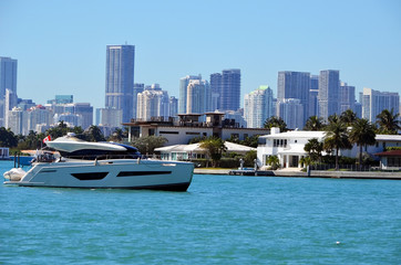 View of a white motor yacht cruising on Biscayne Bay, luxury homes non Riva Alta island in Miami...