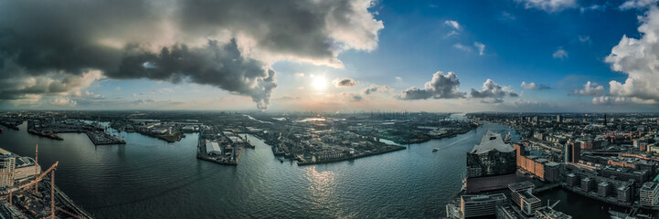 Panoramic aerial drone view of port of Hamburg from Hafencity before sunset with dramatic stormy clouds