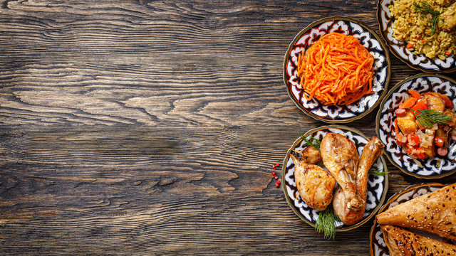 Eastern cuisine. Homemade Uzbek dishes, pilaf, chicken, samsa, Korean carrot salad on a wooden background. baner background image, copy space text, top view