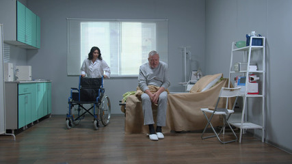 Doctor help old patient to sit in a wheelchair in hospital