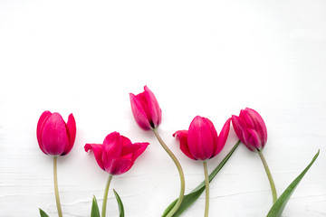 Bouquet of pink tulips on white wooden background, top view