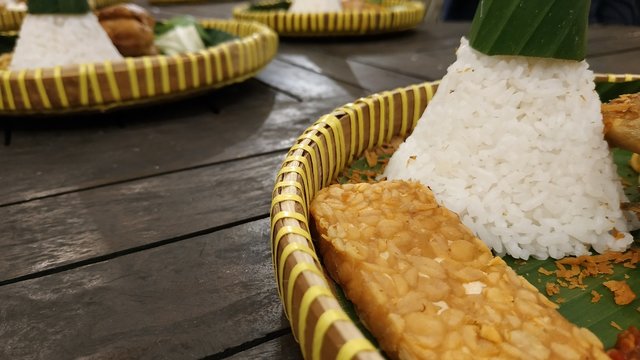 Tumpeng rice aka Nasi Tumpeng is an authentic or traditional Indonesian food consisting of noodles and vegetables with wooden background