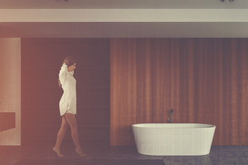 Fototapeta na wymiar Woman walking in wooden bathroom with shelves