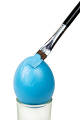 Fototapeta premium Brush painting a Easter egg with blue paint