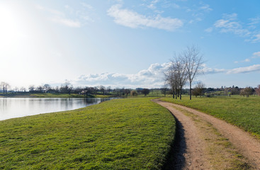 Les eaux calmes du lac de Lapeyrouse dans le Puy-de-Dôme sous un ciel bleu d'hiver. Sentier de promenade autour du lac bordé d'une pelouse verdoyante